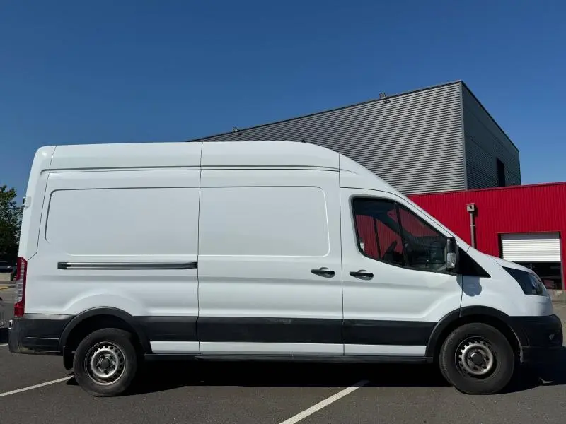 Vue de profil côté droit d'un Ford Transit Fourgon blanc glacier avec porte latérale coulissante et toit haut.