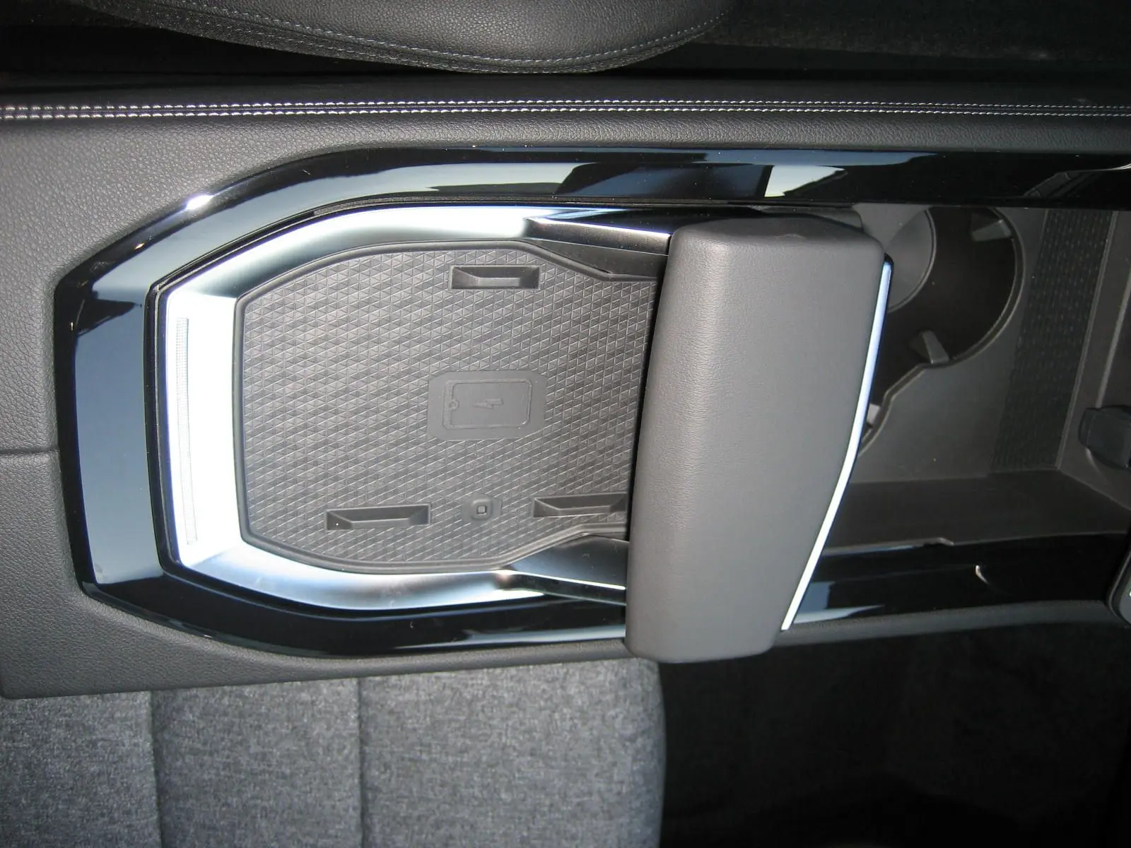 Gros plan sur la console centrale noire du Renault Austral 2025, mettant en valeur le chargeur sans fil et l'accoudoir.