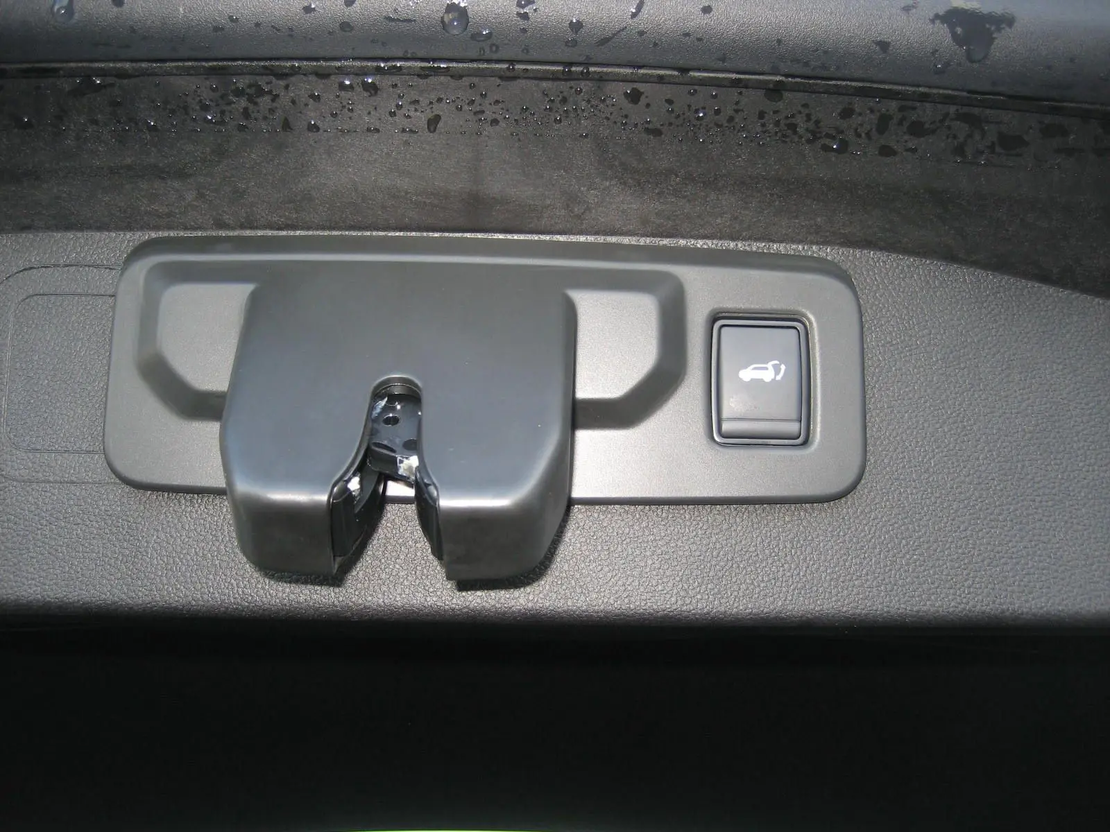 Gros plan sur le mécanisme de verrouillage et le bouton d'ouverture électrique du hayon du Renault Austral bleu outremer.