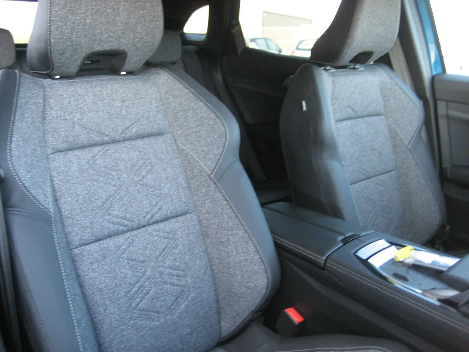 Gros plan sur les sièges avant gris tissu et cuir du Renault Austral PH.2, avec console centrale visible entre eux.