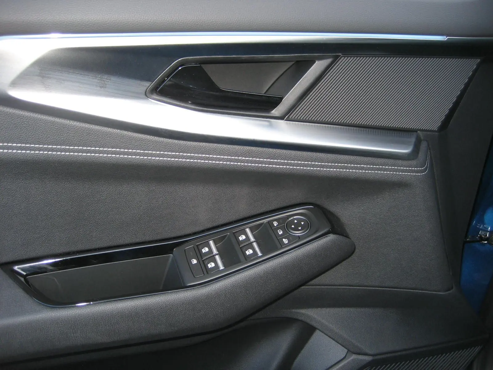 Détail de la porte côté gauche du Renault Austral 2025 bleu outremer, montrant les commandes des vitres et la poignée intérieure.