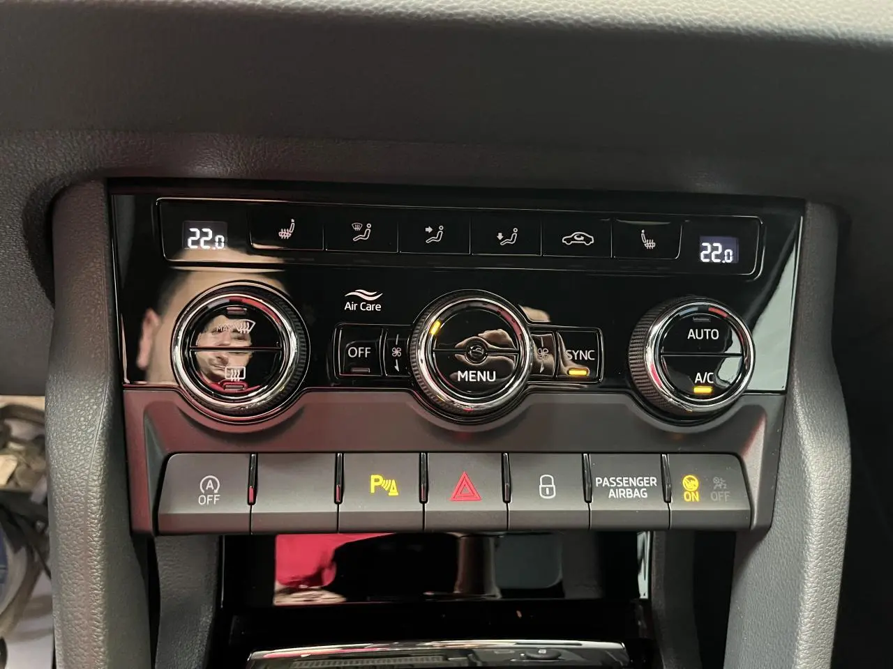 Détail de la console de climatisation automatique tri-zone du Skoda Karoq blanc, avec commandes digitales et boutons rétroéclairés.