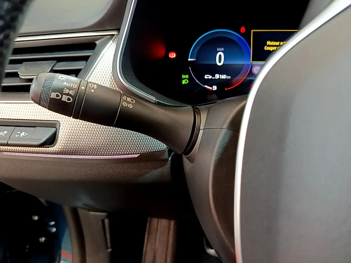 Gros plan sur la manette des feux et le tableau de bord numérique bleu du Renault Arkana Techno E-Tech 2023.