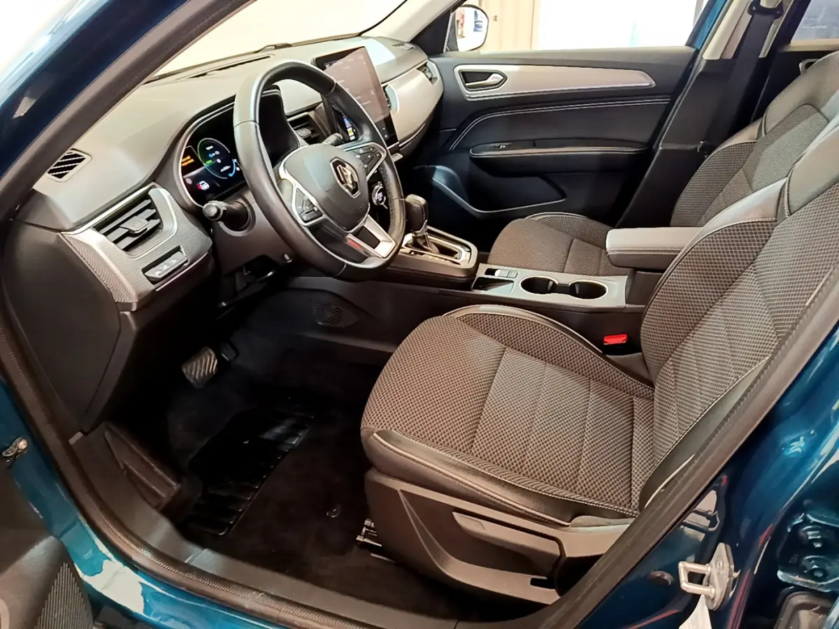 Vue intérieure côté conducteur de la Renault Arkana bleu, avec tableau de bord digital et sièges tissu gris.