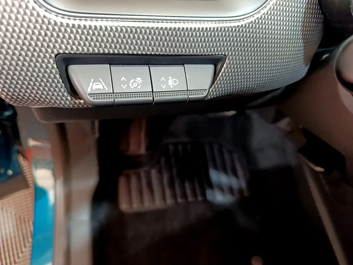 Gros plan sur les boutons de réglage d'assistance et éclairage sous le tableau de bord d'une Renault Arkana bleu.