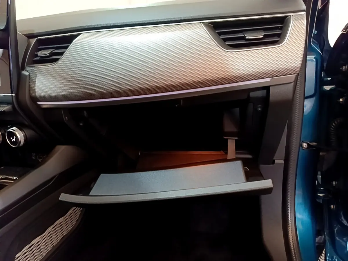 Vue intérieure côté passager du coffre à gants ouvert du Renault Arkana bleu, soulignant la texture du tableau de bord.