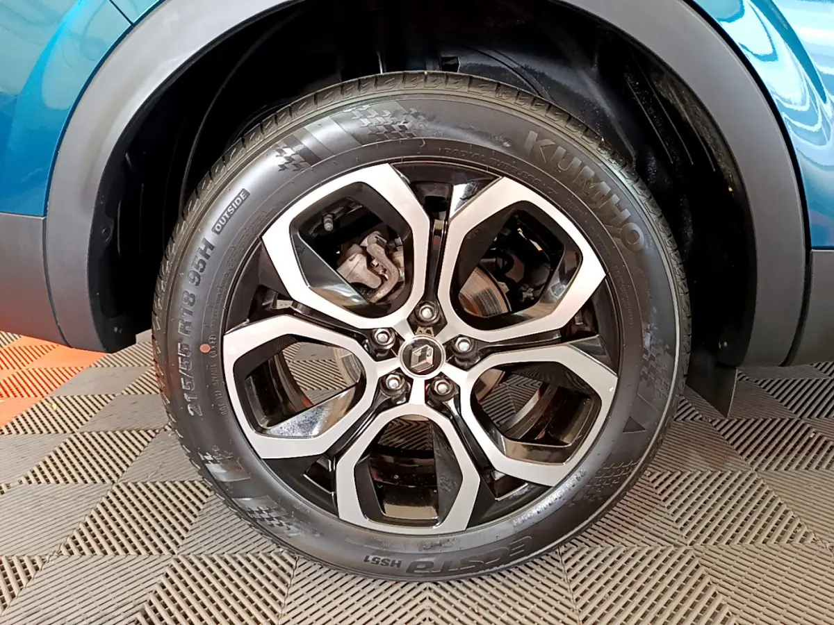 Gros plan sur la roue avant droite bleu métallisé du Renault Arkana Techno E-Tech avec jante alliage noire et argent.