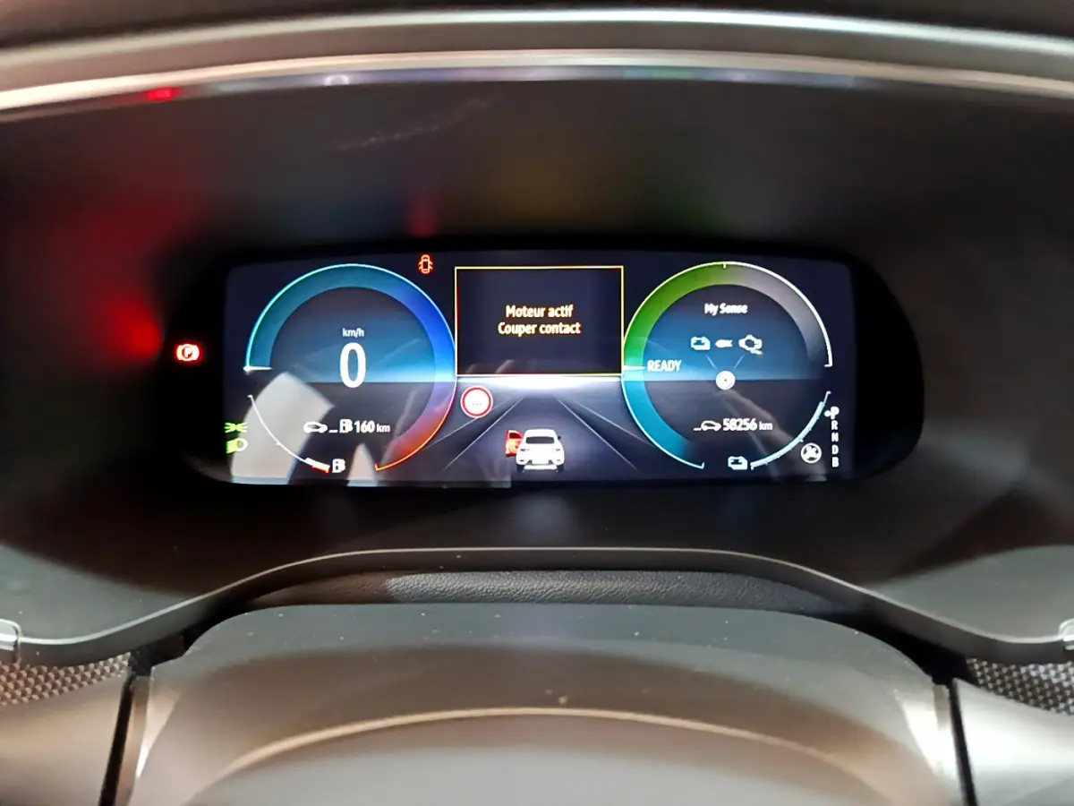 Vue rapprochée du tableau de bord numérique du Renault Arkana bleu, affichant la vitesse à 0 km/h et l'état moteur actif.