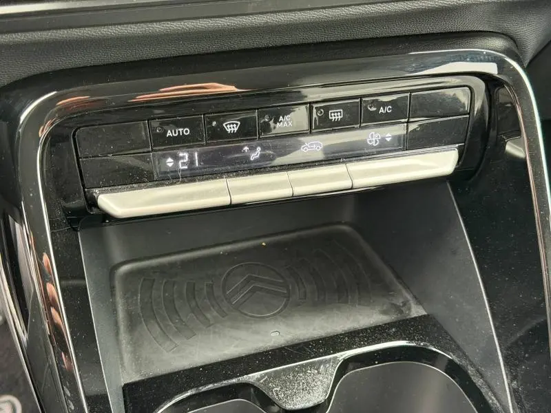 Vue rapprochée de la console centrale de la Citroën C3 2025 noire, montrant les commandes de climatisation et un espace de rangement avec logo Citroën.