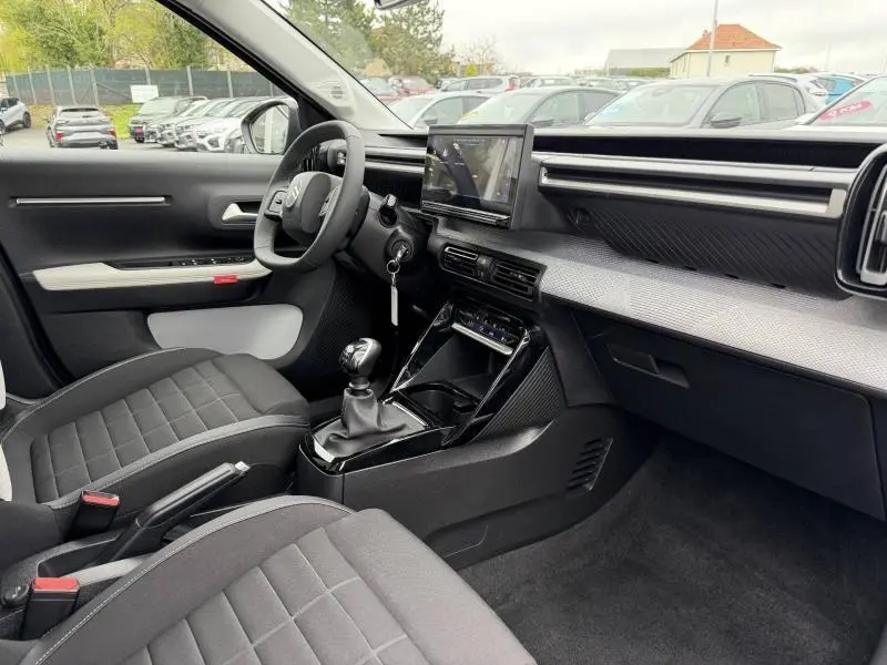 Vue intérieure côté conducteur de la Citroën C3 1.2 Turbo 100ch MAX 2025 avec boîte manuelle et tableau de bord moderne noir.