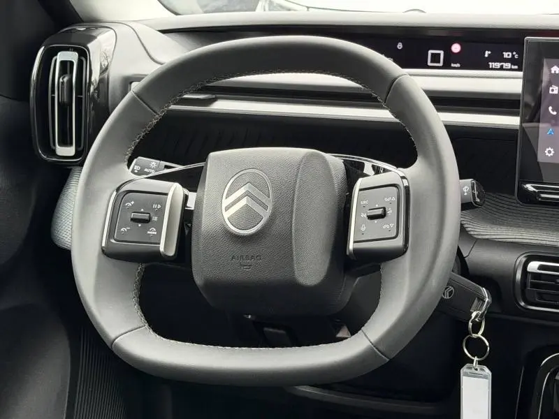 Vue rapprochée du volant cuir noir de la Citroën C3 2025 avec commandes intégrées et tableau de bord numérique.