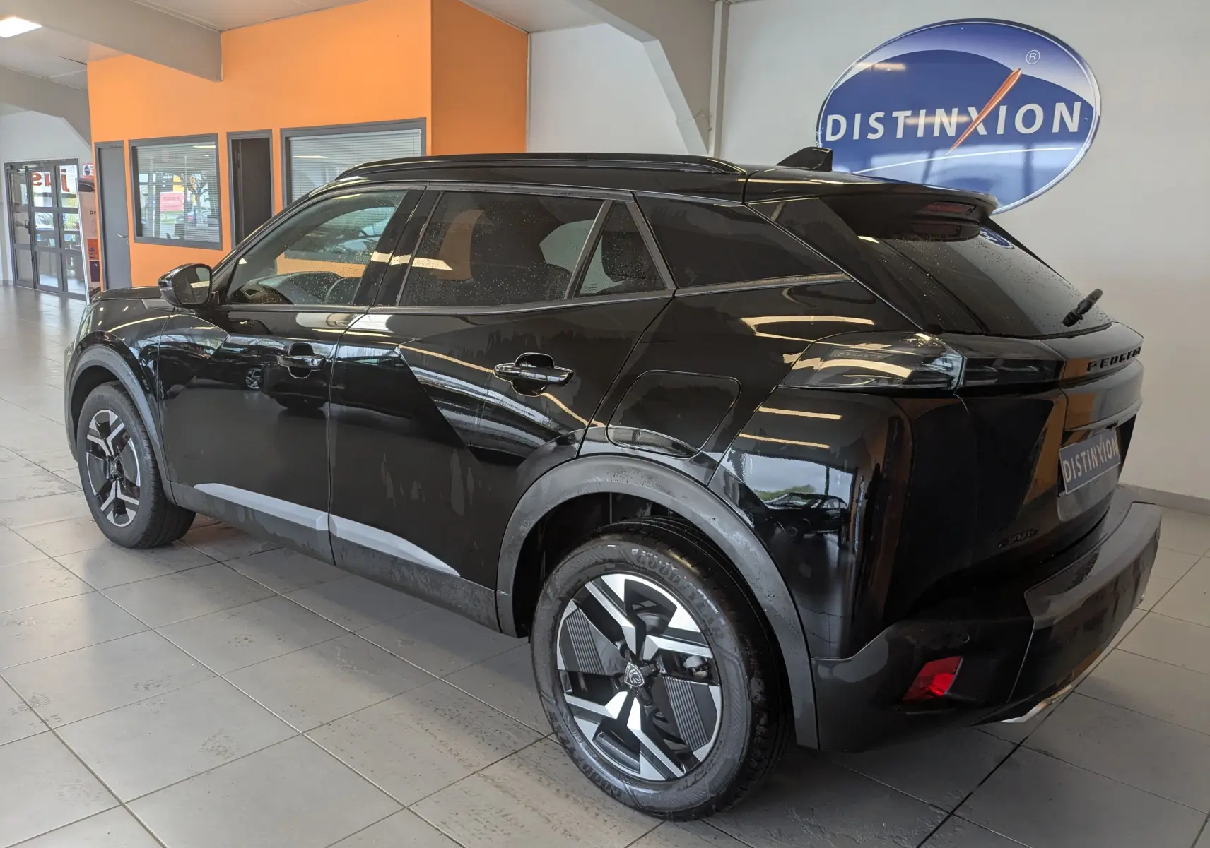 Peugeot 2008 noir 3/4 arrière droit en intérieur, avec jantes bi-ton et toit noir brillant.