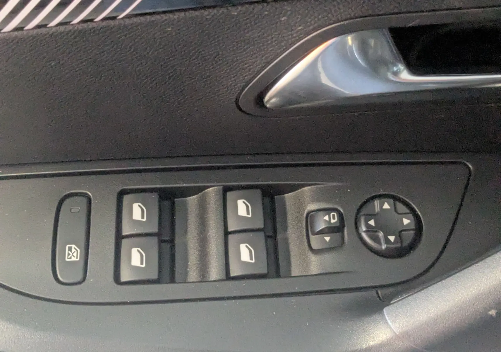 Gros plan sur les commandes des vitres et rétroviseurs côté conducteur d’un Peugeot 2008 noir 2024.