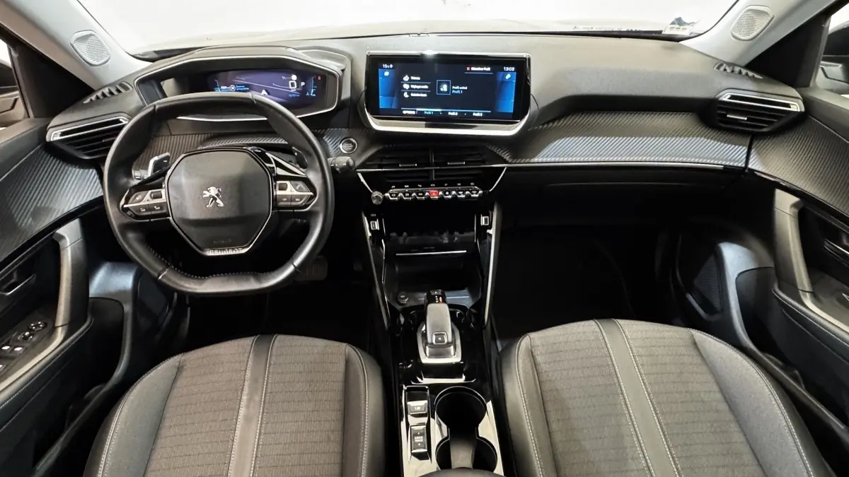 Vue intérieure frontale du poste de conduite gris foncé du Peugeot 2008 avec écran tactile central et volant compact multifonctions.