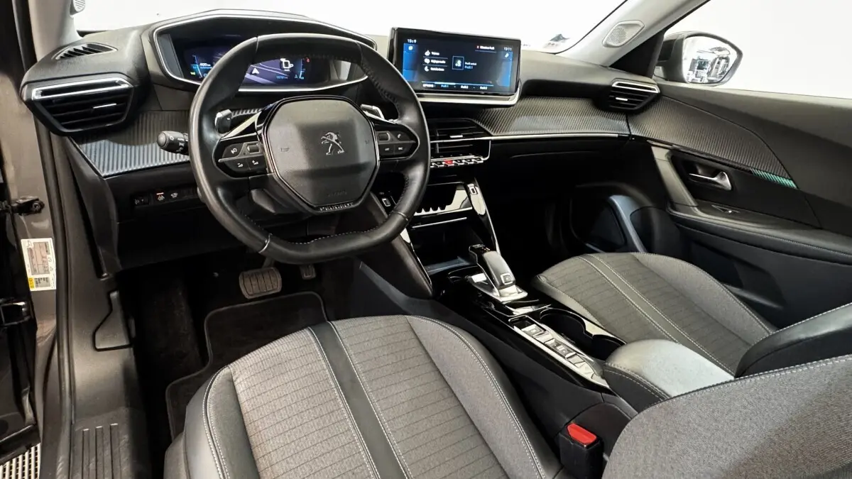 Intérieur avant droit du Peugeot 2008 gris foncé 2022, volant compact, écran tactile et sièges tissu gris.