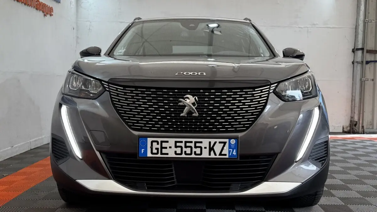 Vue frontale d'un Peugeot 2008 gris foncé avec calandre noire et feux diurnes LED verticaux allumés.