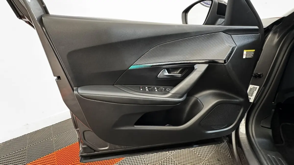 Vue intérieure de la porte avant gauche du Peugeot 2008 gris foncé, avec commandes électriques et insert décoratif noir texturé.