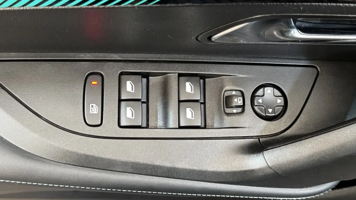 Vue rapprochée des commandes de lève-vitres et réglage des rétroviseurs sur la porte côté conducteur d’un Peugeot 2008 gris foncé.