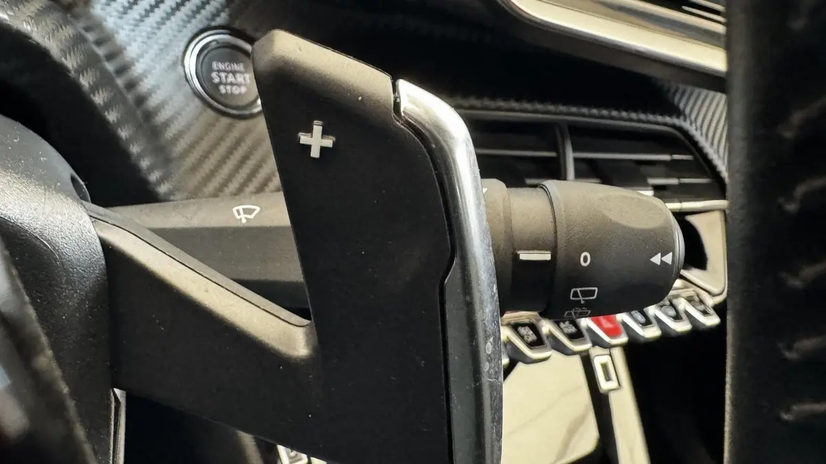 Gros plan sur la palette de changement de vitesse droite en plastique noir et chrome dans l’habitacle gris foncé du Peugeot 2008 2022.