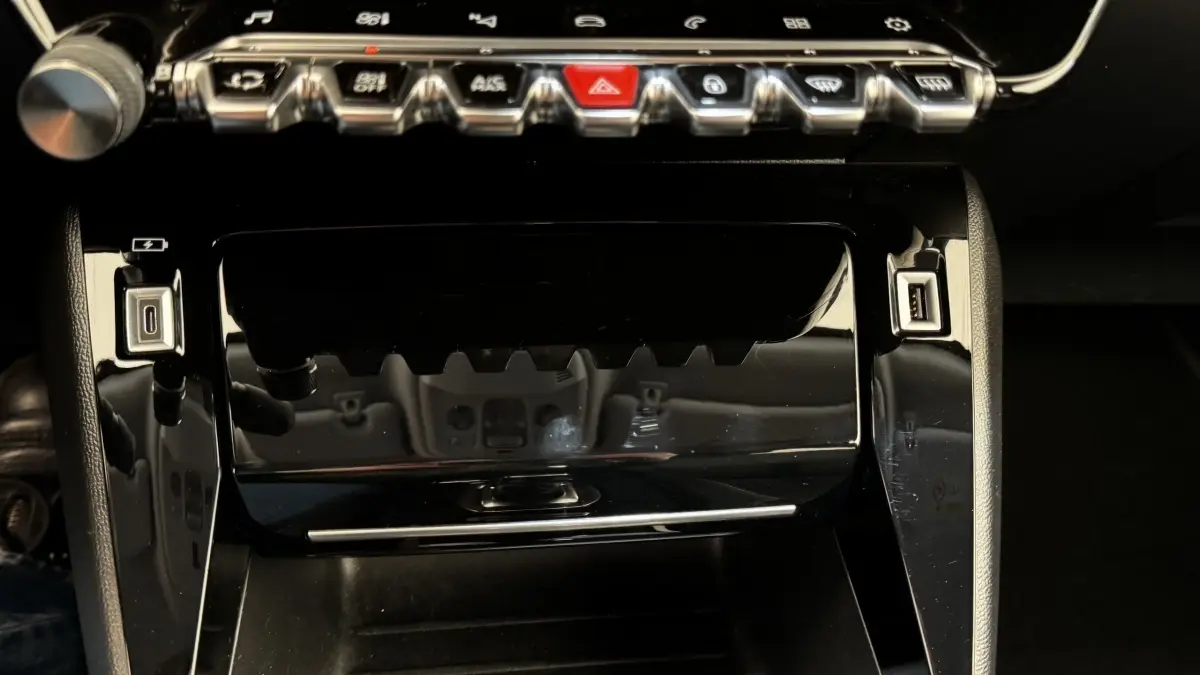Vue rapprochée de la console centrale noire brillante du Peugeot 2008 avec boutons de commande et ports USB visibles.