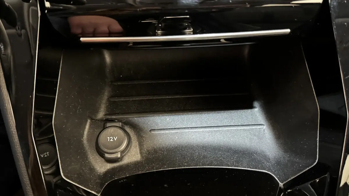 Gros plan sur la prise 12V dans le rangement central noir du Peugeot 2008 PureTech 130 S&S EAT8 Allure Pack 2022.