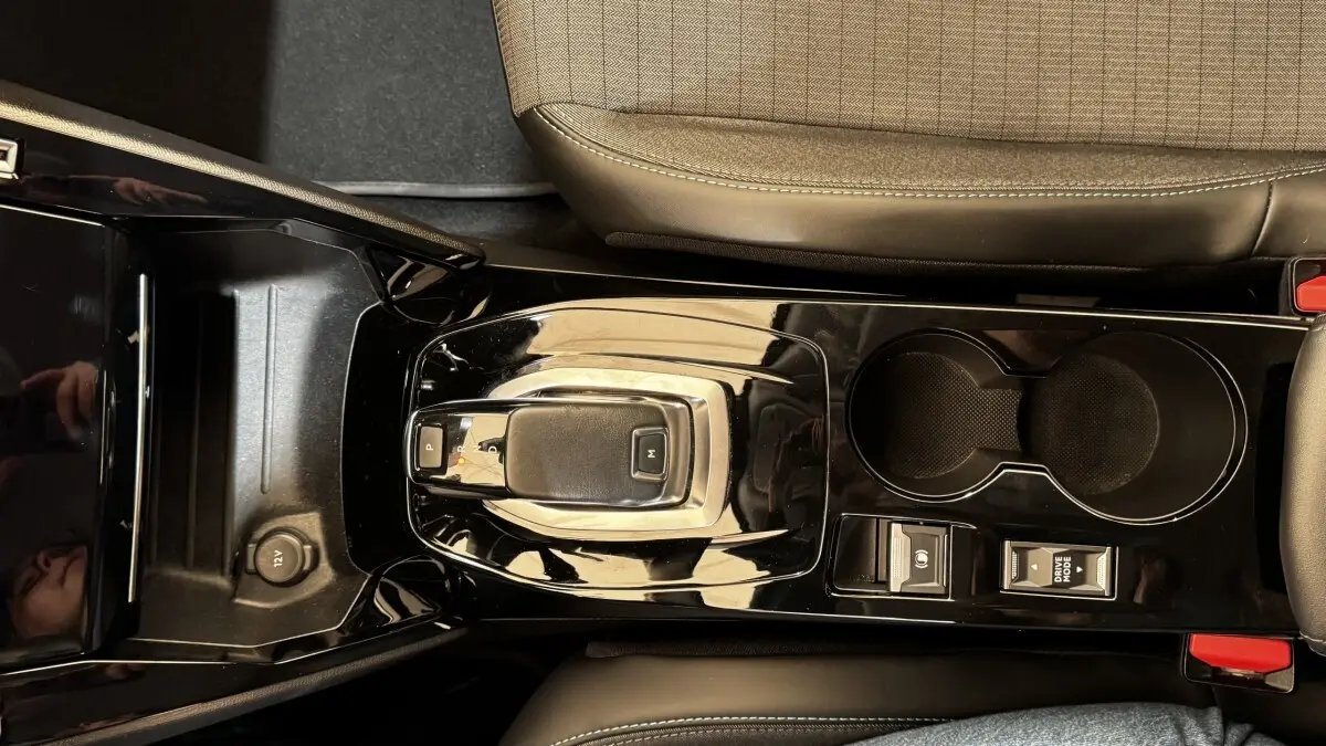 Vue plongeante sur la console centrale noire brillante du Peugeot 2008 gris foncé, avec levier de vitesse automatique et porte-gobelets.