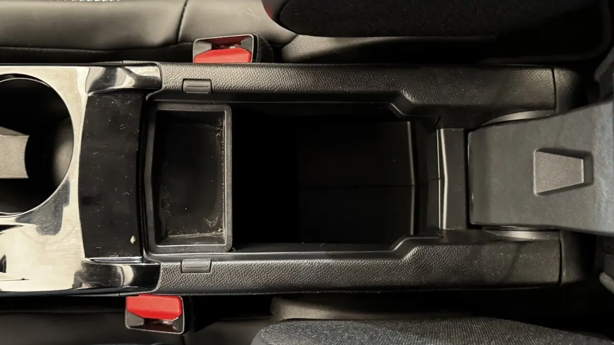 Vue plongeante sur la console centrale noire avec rangement ouvert et porte-gobelets du Peugeot 2008 gris foncé 2022.