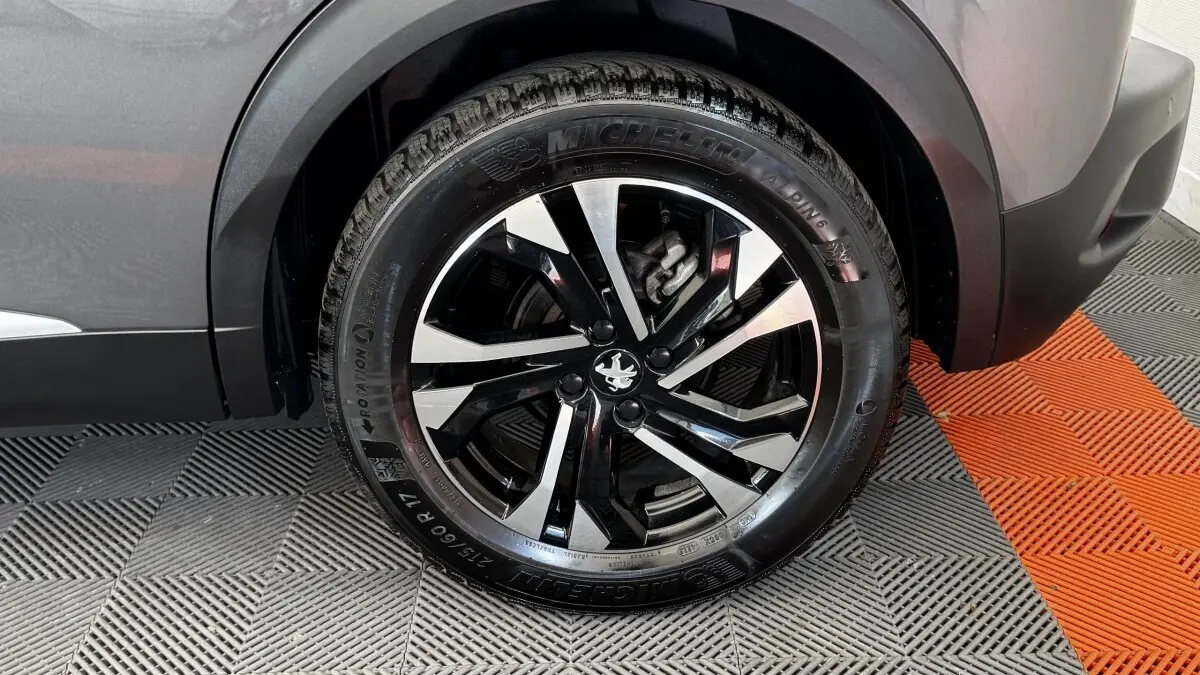 Gros plan sur la roue arrière droite du Peugeot 2008 gris foncé, mettant en valeur la jante alliage noire et argentée.