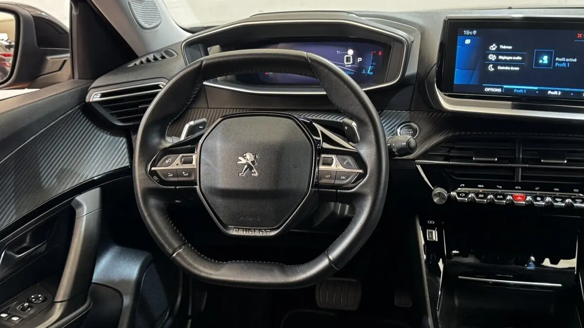 Vue intérieure centrée sur le volant cuir multifonctions et le tableau de bord numérique du Peugeot 2008 gris foncé 2022.