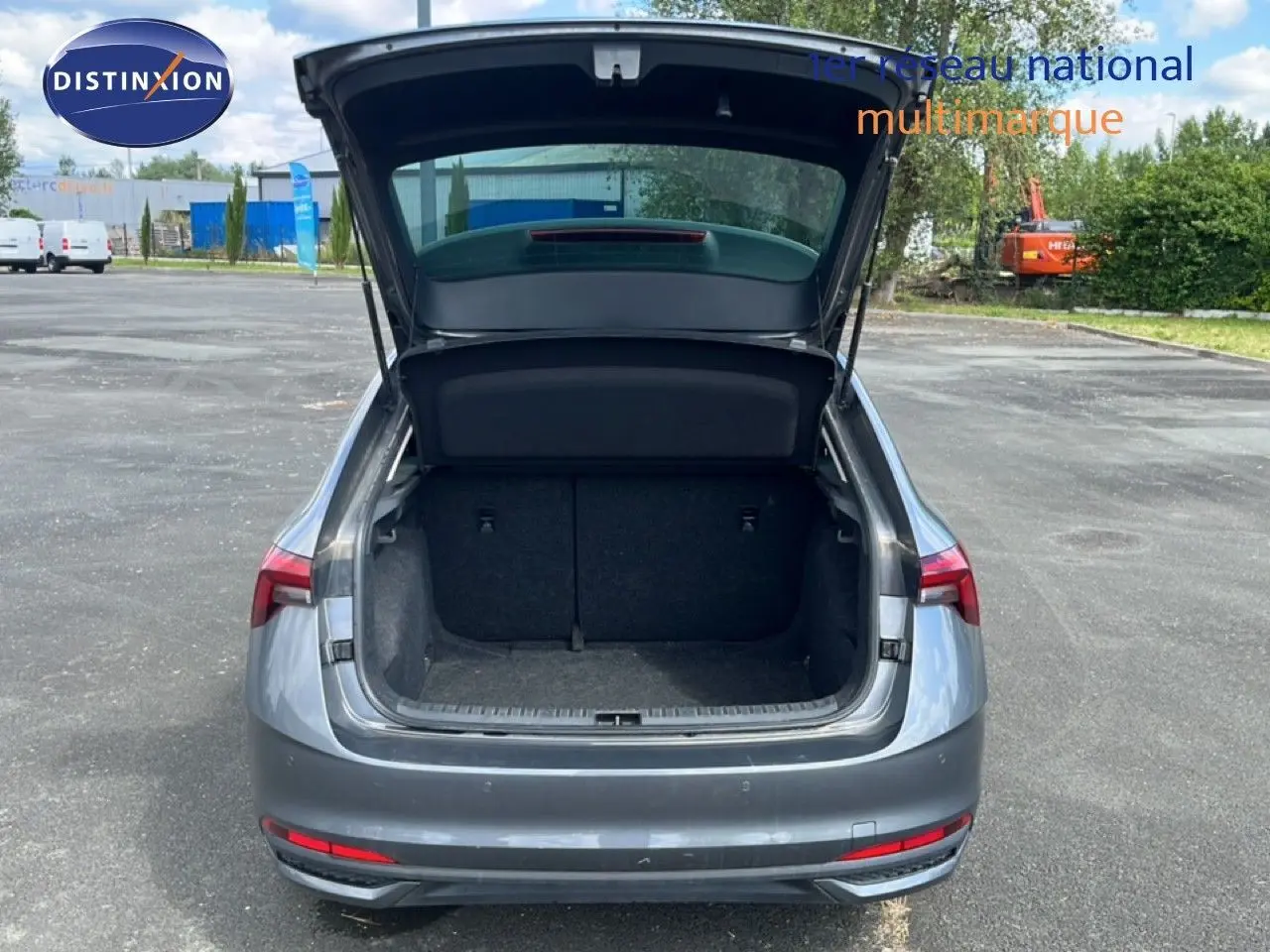 Vue arrière d'une Skoda Scala gris magnétique métal avec coffre ouvert sur un parking extérieur.
