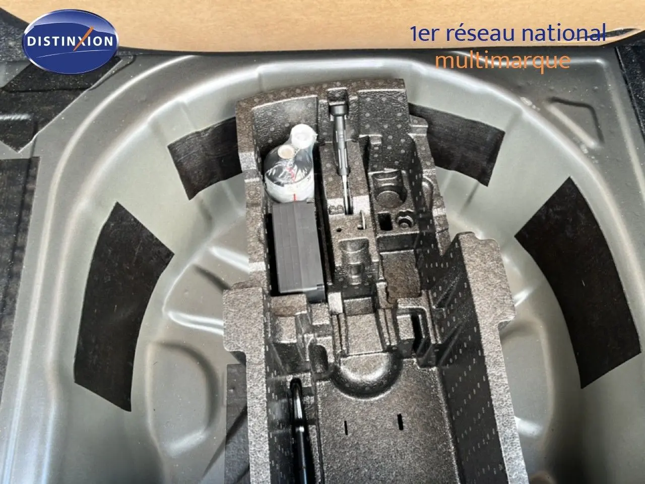 Vue plongeante sur le rangement de roue de secours du Skoda Scala gris magnétique, montrant les compartiments d’outils intégrés.