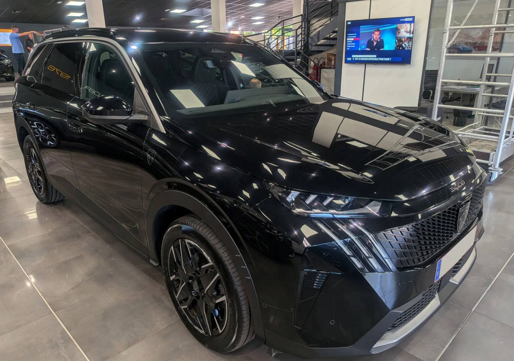 Peugeot 5008 Hybrid 145 GT noir Perla en 3/4 avant droit, avec jantes noires et calandre distinctive.