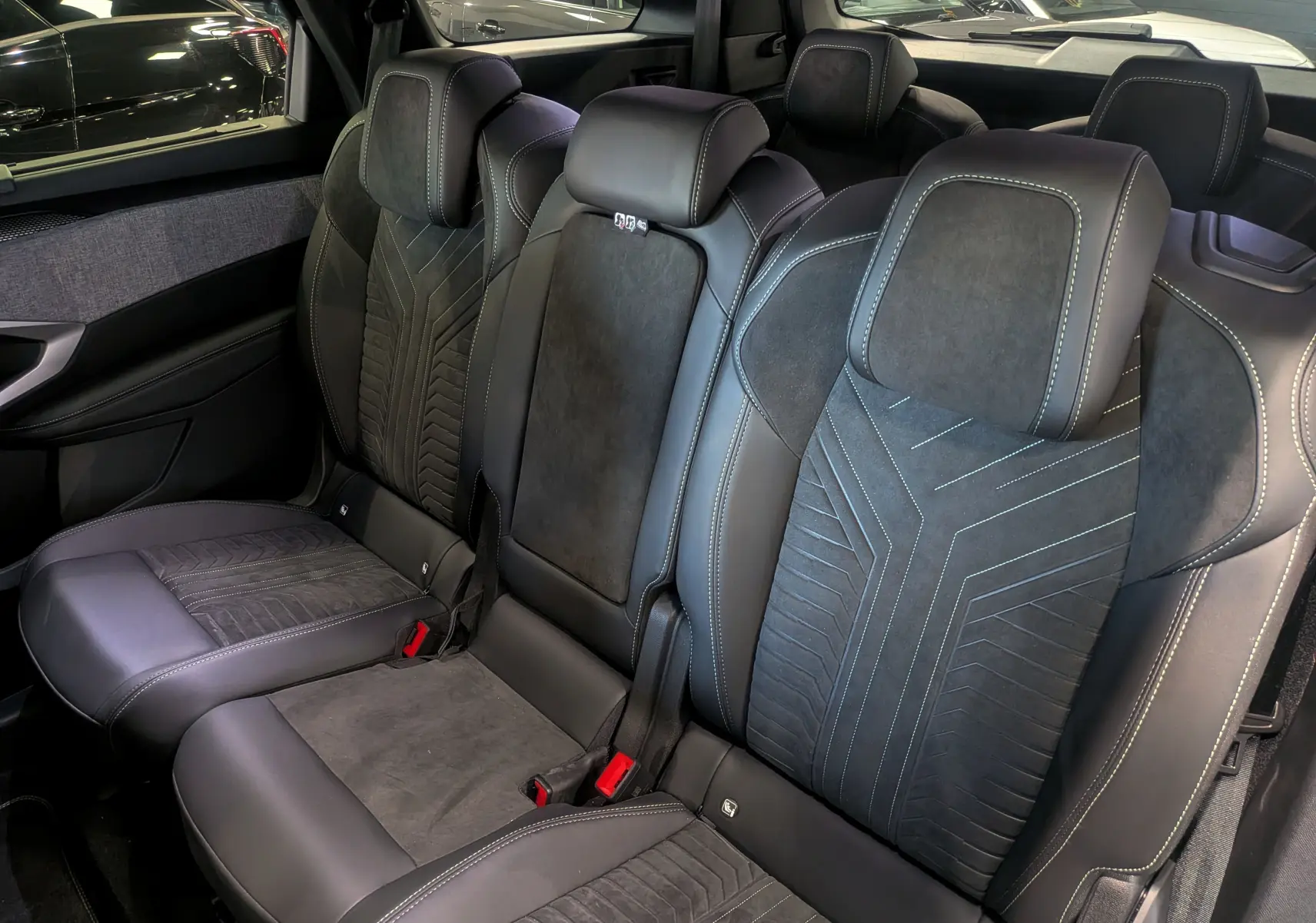 Vue intérieure sur la banquette arrière en cuir noir et alcantara du Peugeot 5008 Hybrid 145 GT 2025, avec surpiqûres contrastées.