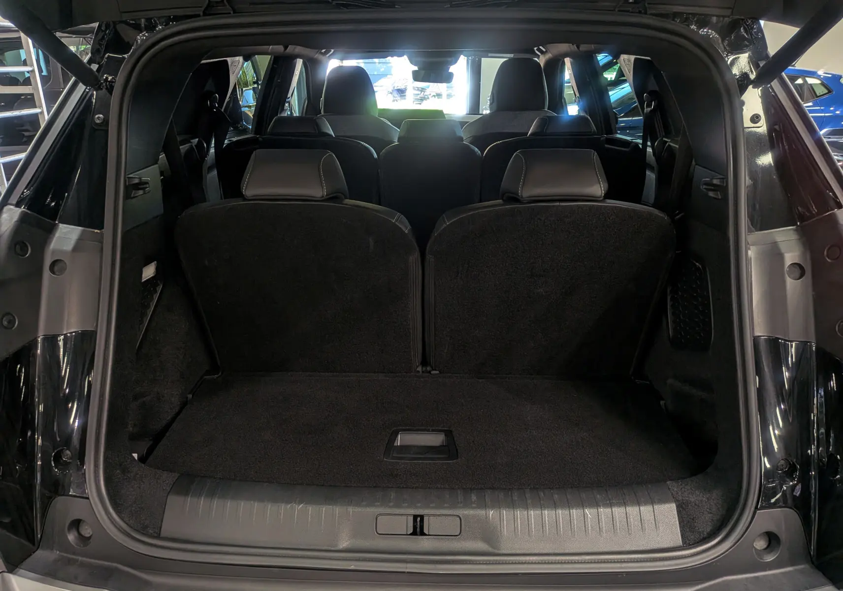 Vue arrière ouverte du coffre du Peugeot 5008 HYBRID 145 CH e-DCS6 GT noir Perla, montrant les sièges arrière et la capacité de chargement.
