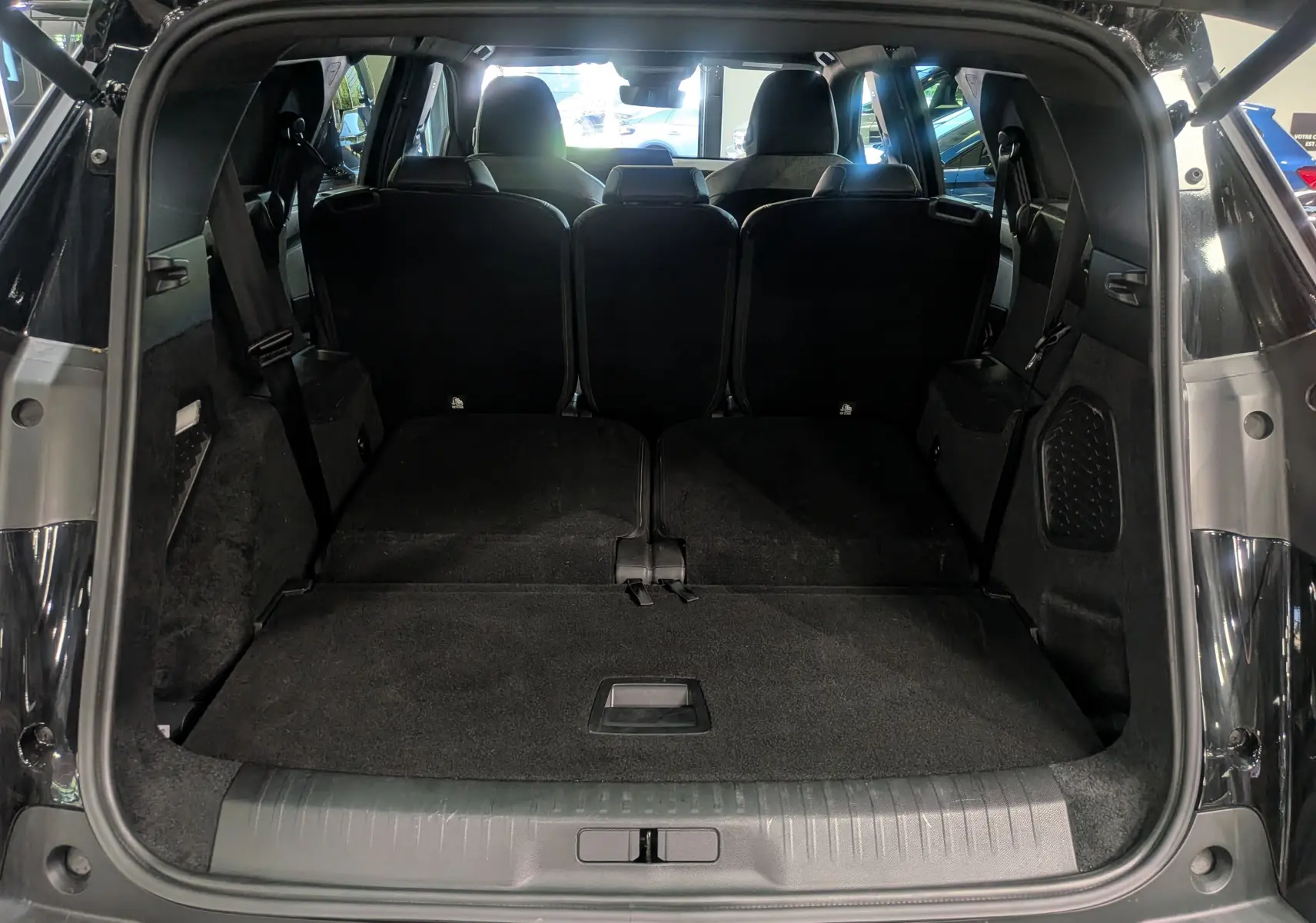 Vue arrière du coffre ouvert du Peugeot 5008 Hybrid 145 CH e-DCS6 GT noir Perla avec sièges rabattus offrant un grand espace de chargement.
