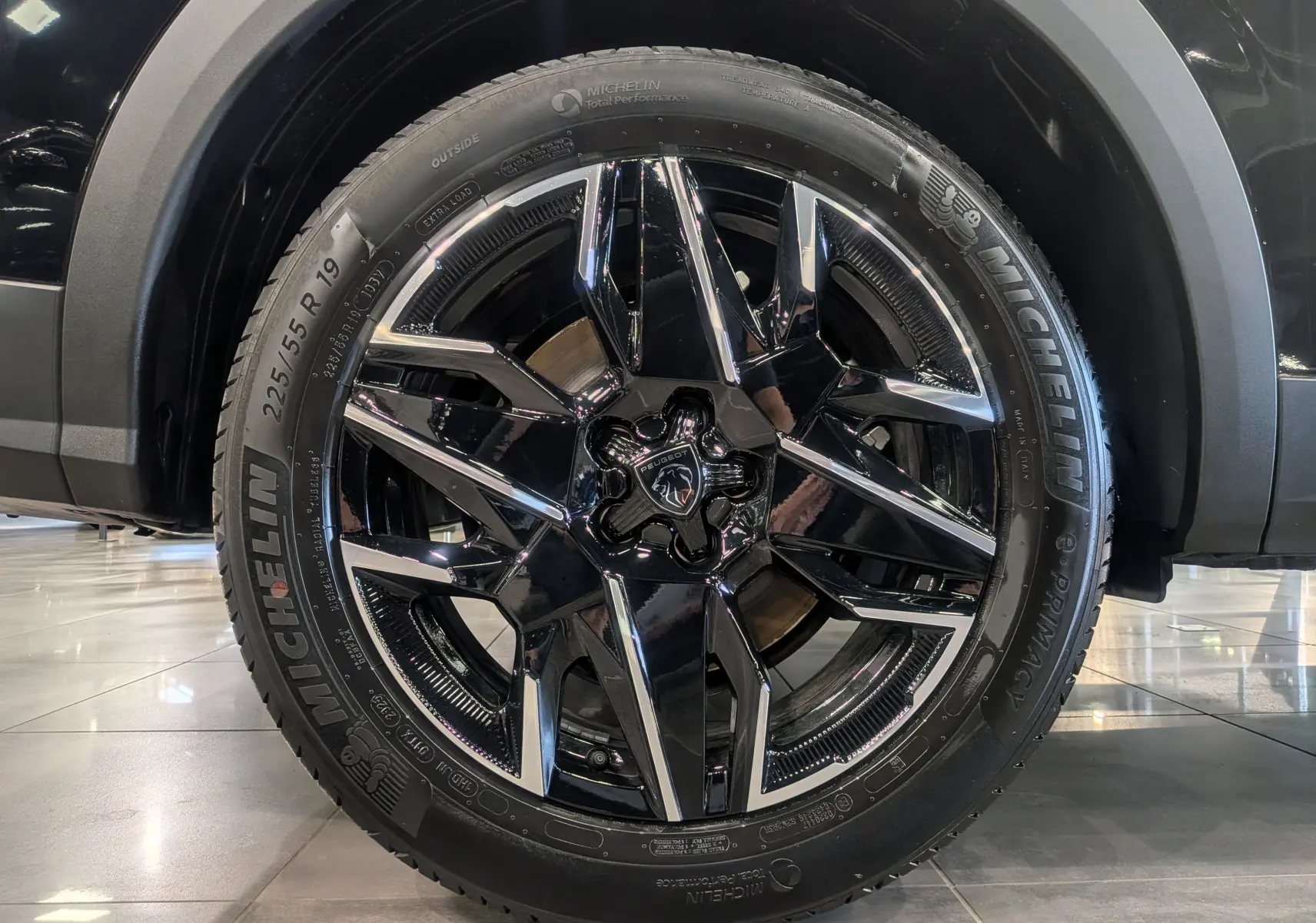 Gros plan sur la roue avant droite du Peugeot 5008 Hybrid 145 GT noir Perla avec jante alliage noir et inserts chromés.