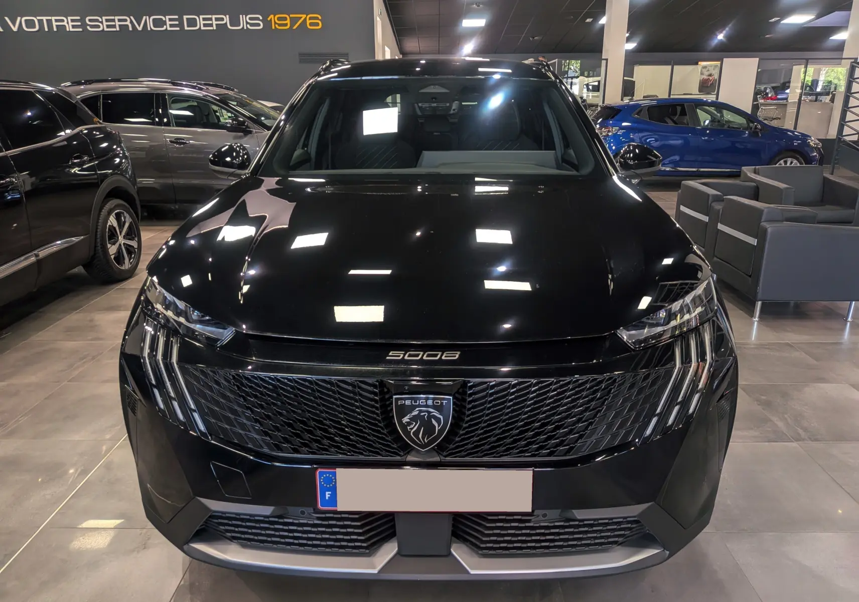 Vue avant d'un Peugeot 5008 Hybrid 145 ch e-DCS6 GT noir Perla, avec calandre noire et logo lion central lumineux.