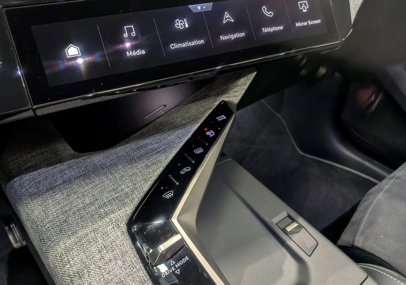 Vue rapprochée de la console centrale et écran tactile du Peugeot 5008 Hybrid 145 GT 2025 avec finition tissu gris et commandes tactiles.