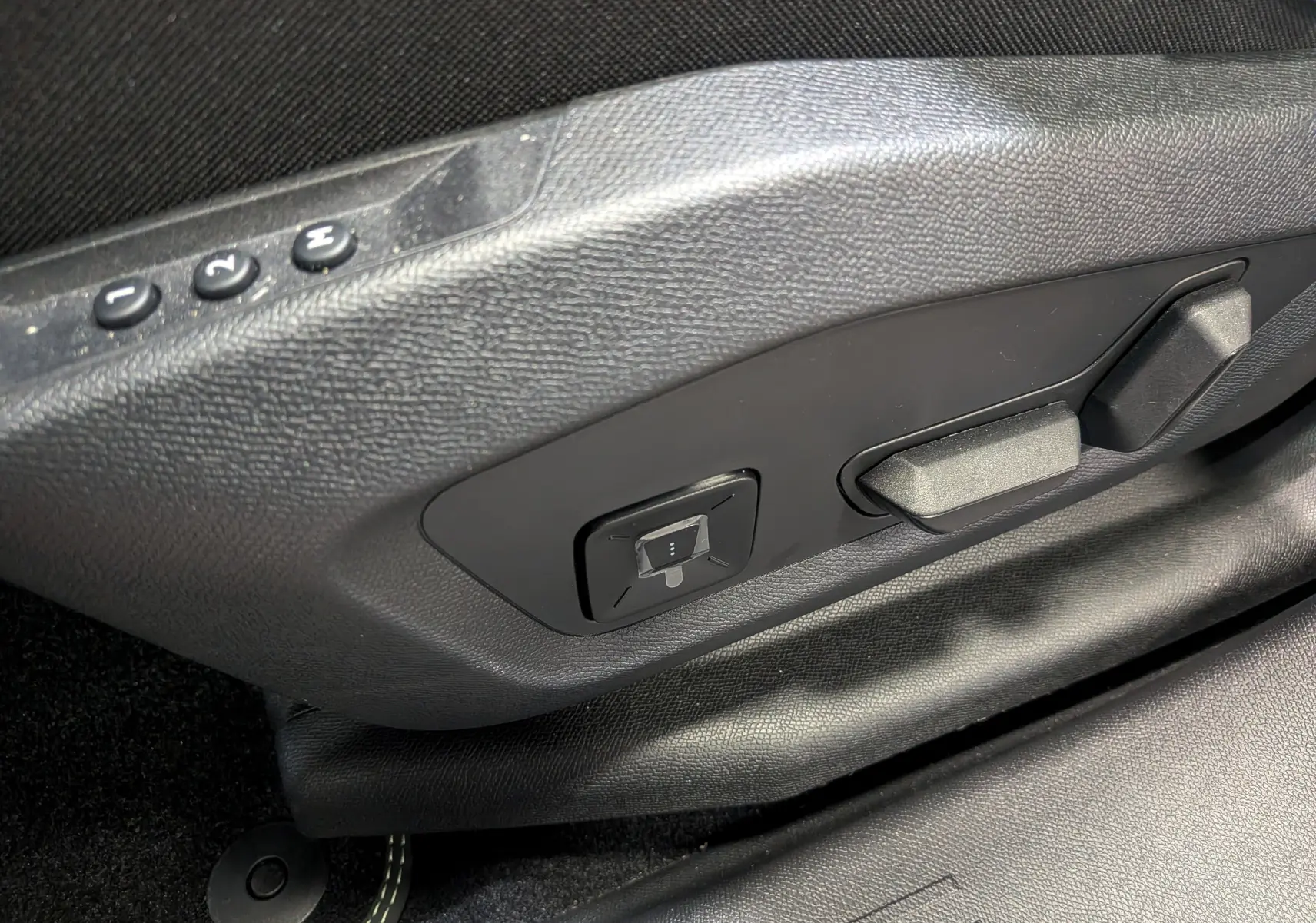 Gros plan sur les commandes de réglage électrique du siège côté gauche, intérieur noir du Peugeot 5008 Hybrid 2025.