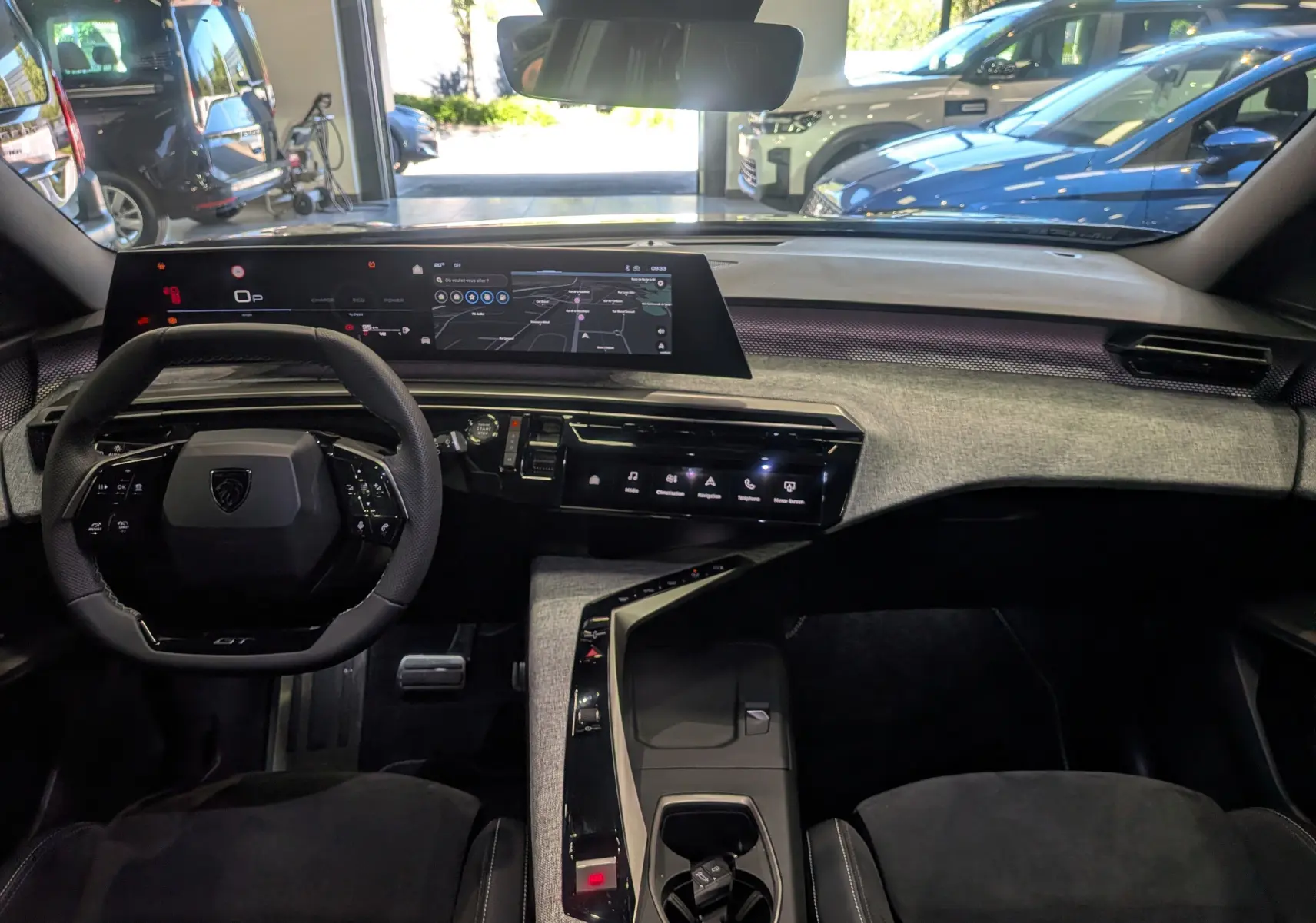 Vue intérieure frontale du tableau de bord du Peugeot 5008 Hybrid 145 GT 2025, avec écran tactile et volant compact noir.