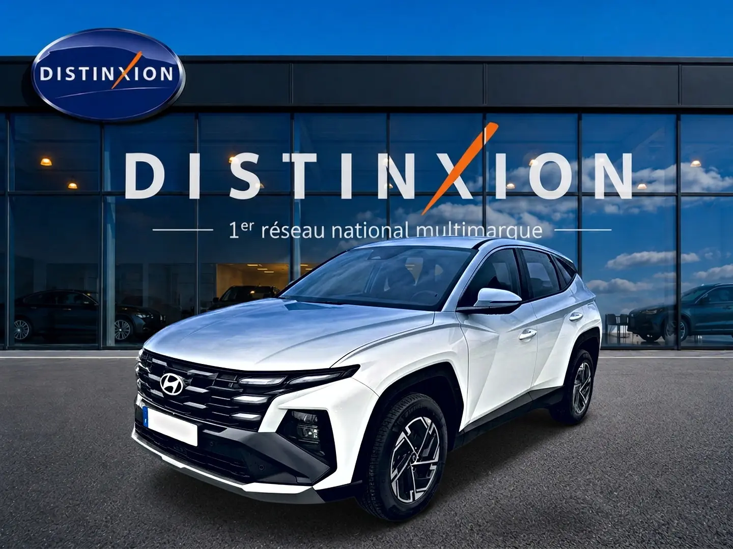 Hyundai Tucson blanc vu en 3/4 avant droit, avec calandre noire et jantes alliage 17 pouces distinctives.