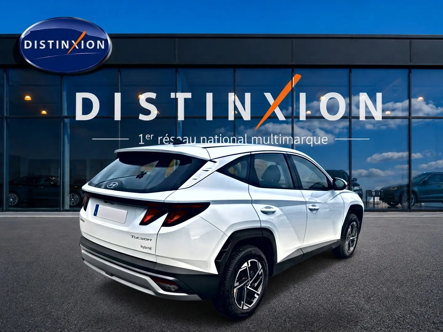 Hyundai Tucson hybride blanc en 3/4 arrière droit, avec jantes alliage et feux arrière LED distinctifs.