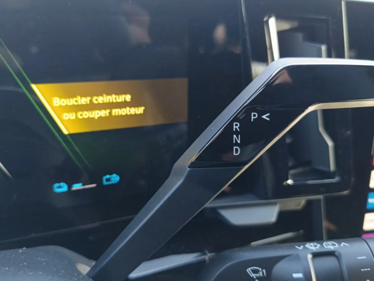 Détail intérieur du levier de vitesses automatique et écran multifonctions avec message d'alerte sur Renault Austral blanc.