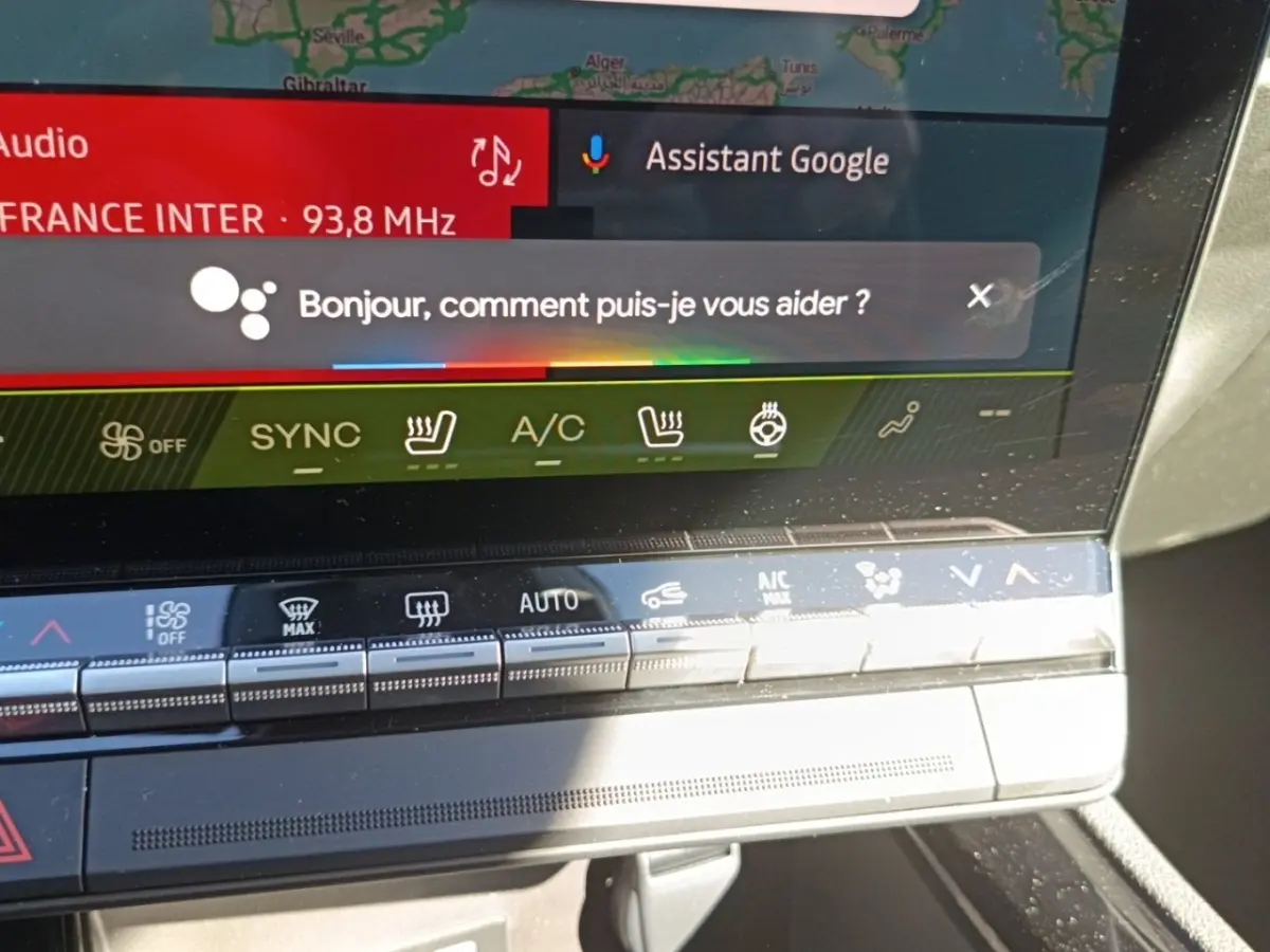 Gros plan sur l'écran tactile central du tableau de bord du Renault Austral blanc, affichant l'assistant Google.