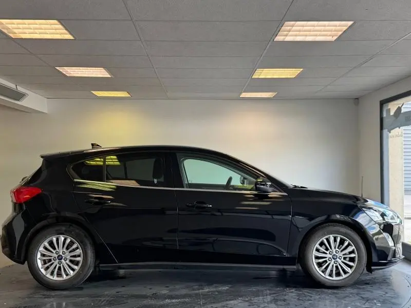 Vue latérale droite d'une Ford Focus 2021 noire Agate métallisé, avec jantes alliage et vitres teintées.