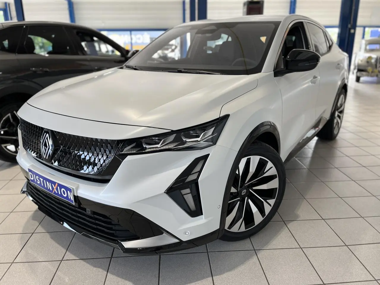 Renault Rafale blanc en 3/4 avant droit, avec calandre noire brillante et jantes alliage bicolores.