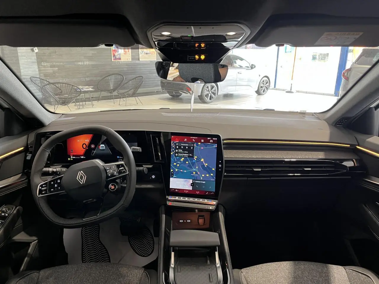 Vue intérieure frontale du tableau de bord de la Renault Rafale blanche avec écran tactile vertical et volant multifonction.