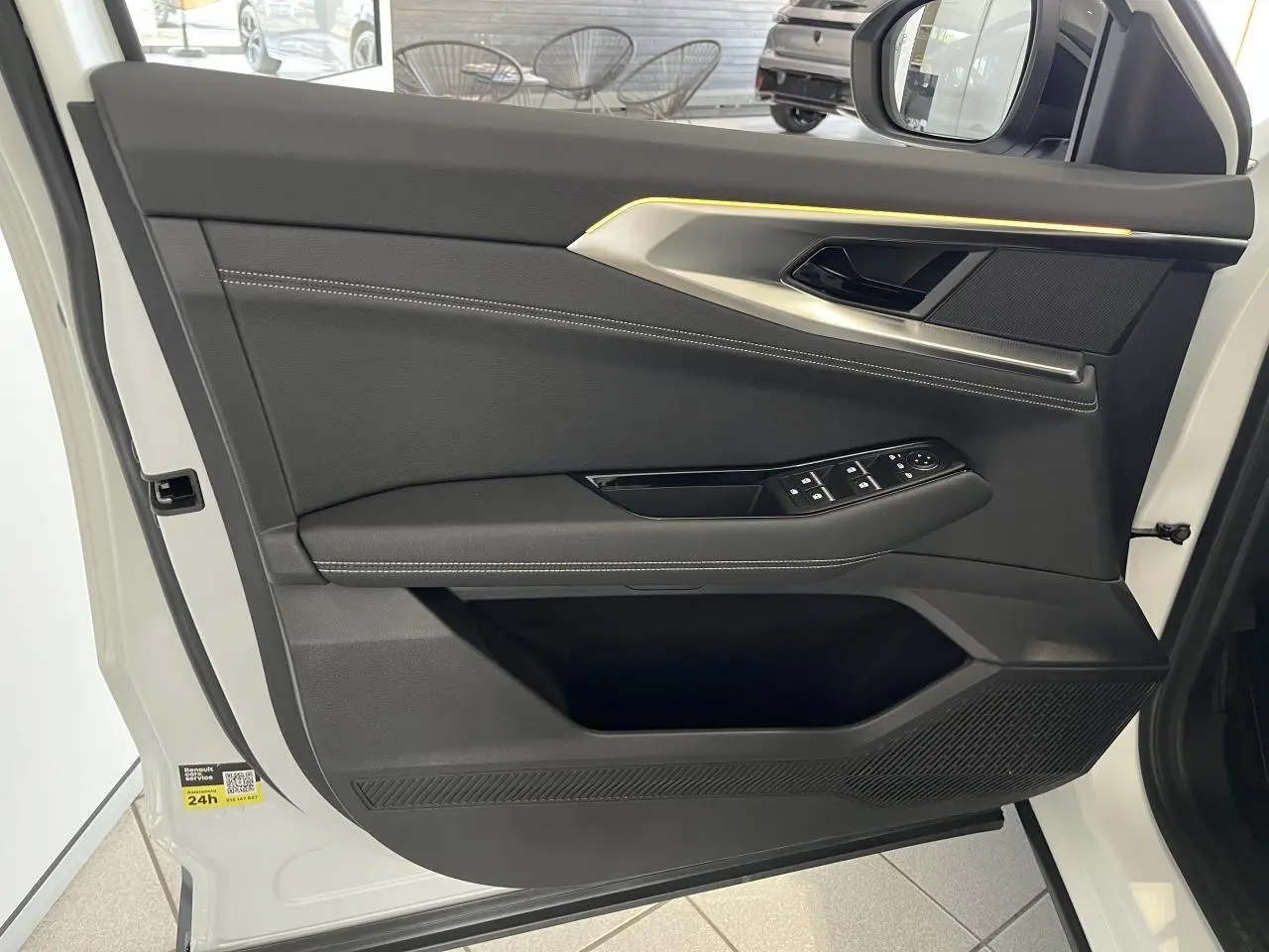 Porte avant gauche ouverte d'une Renault Rafale blanche 2025, avec garniture noire et surpiqûres argentées.