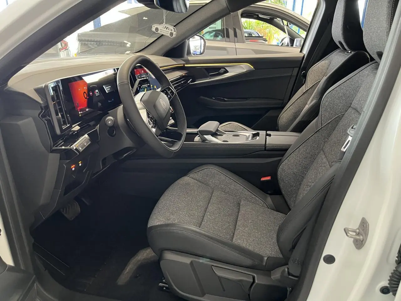 Intérieur côté conducteur de la Renault Rafale blanche 2025, sièges gris textile et tableau de bord numérique.