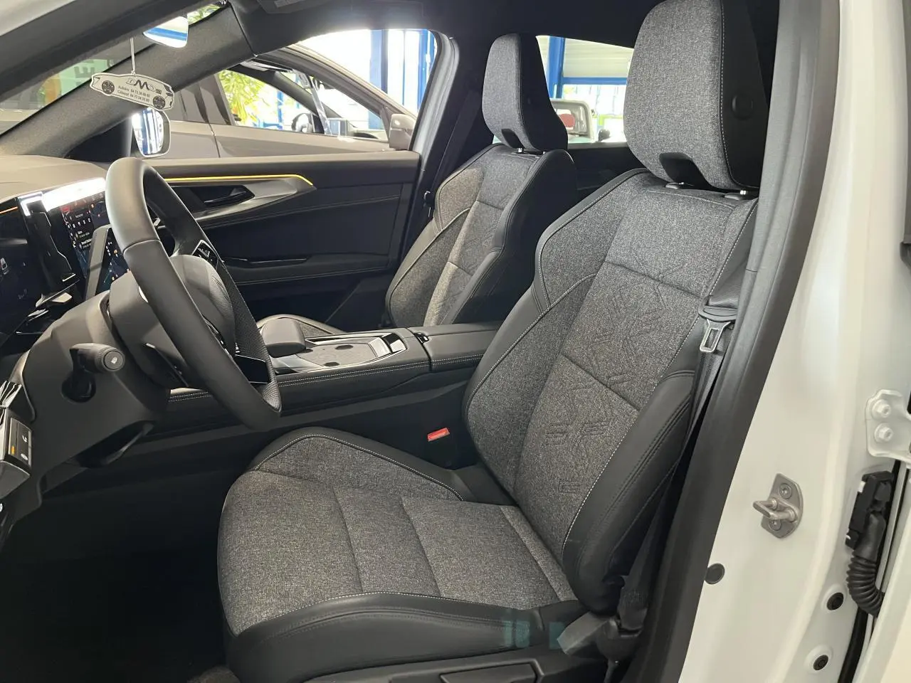 Intérieur avant droit de la Renault Rafale blanche 2025, sièges sport gris textile avec surpiqûres argentées.